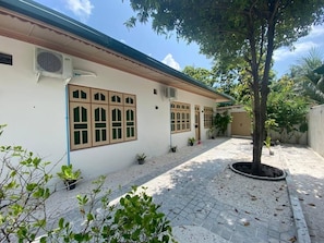 A building with a tiled courtyard, a tree, and potted plants. - Ocean Stay & Dive (Fenfushi)