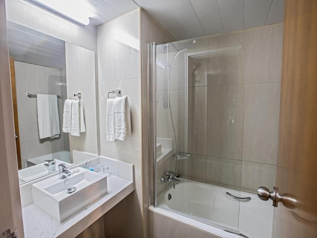 Un baño con ducha de vidrio, lavamanos blanco y espejo.