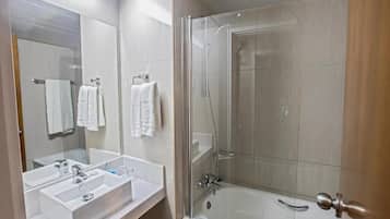 Un baño con ducha de vidrio, lavamanos blanco y espejo.
