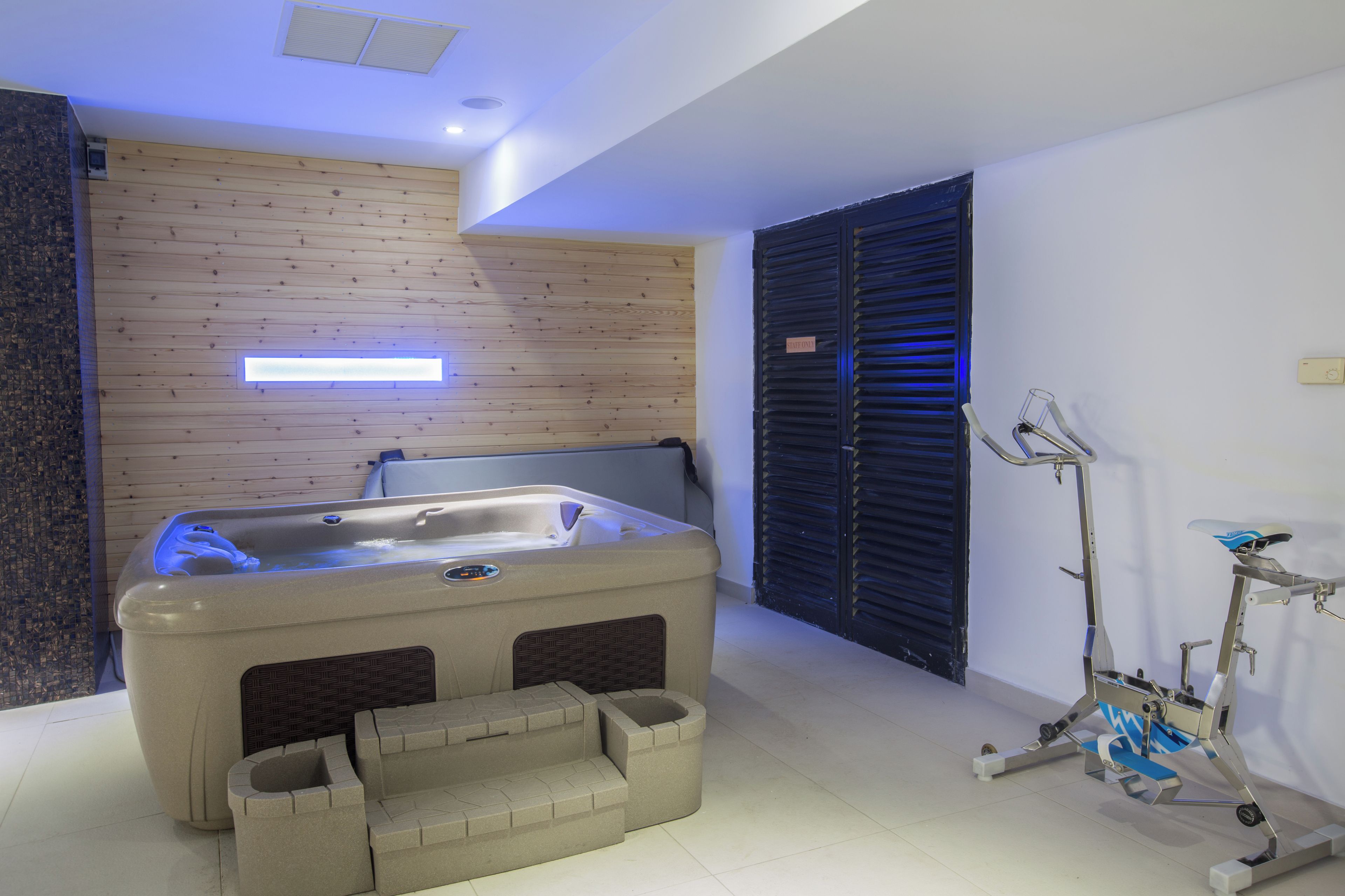Een moderne badkamer met een bad, fitnessapparatuur en een houten wand.