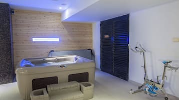 Een moderne badkamer met een bad, fitnessapparatuur en een houten wand.
