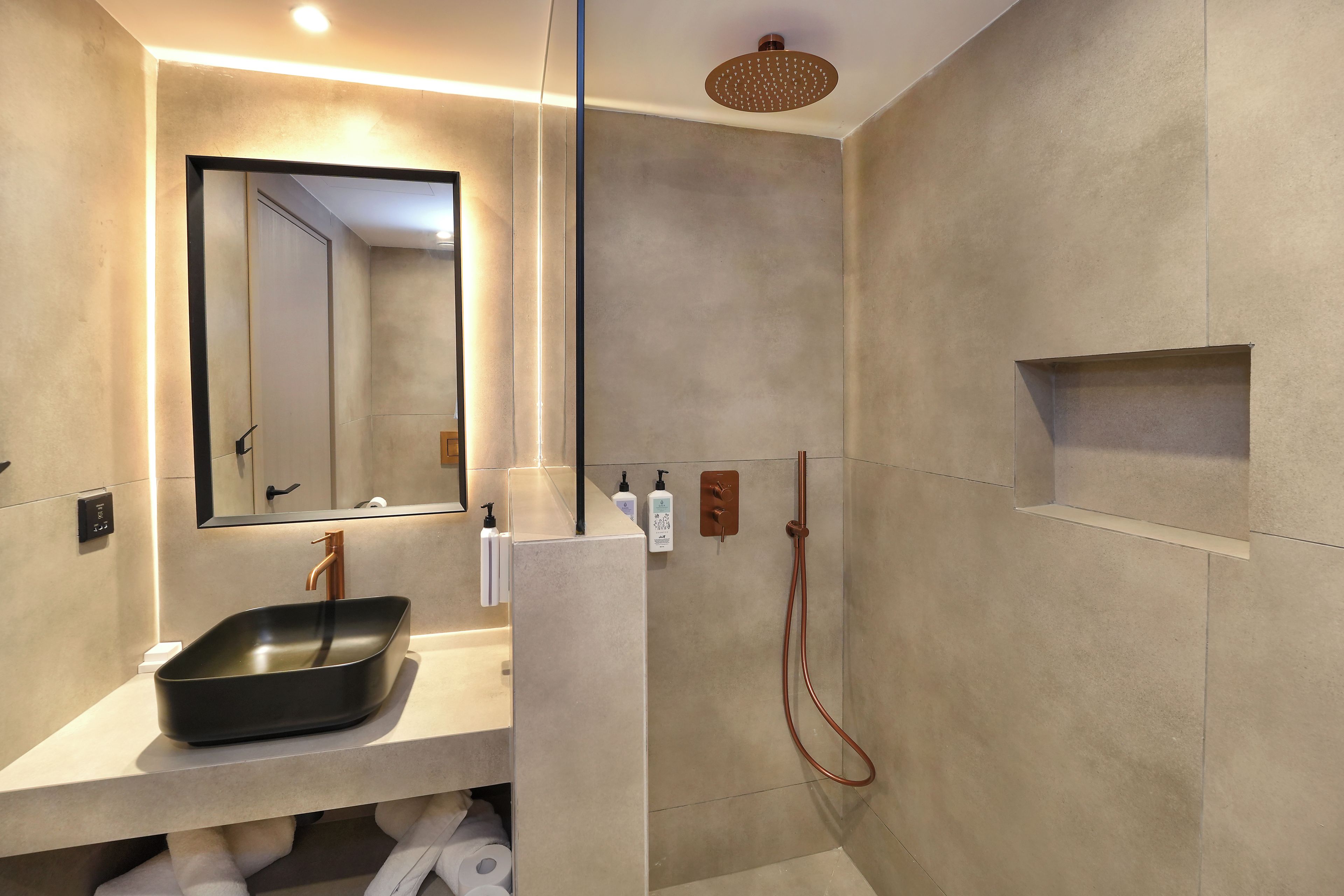 A modern bathroom with a large mirror, a sink, a shower with a handheld showerhead, and a towel rack.