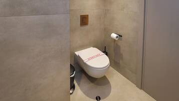Des toilettes modernes avec une étiquette indiquant « STÉRILISÉ », une poignée de chasse d’eau et un porte-rouleau de papier toilette.