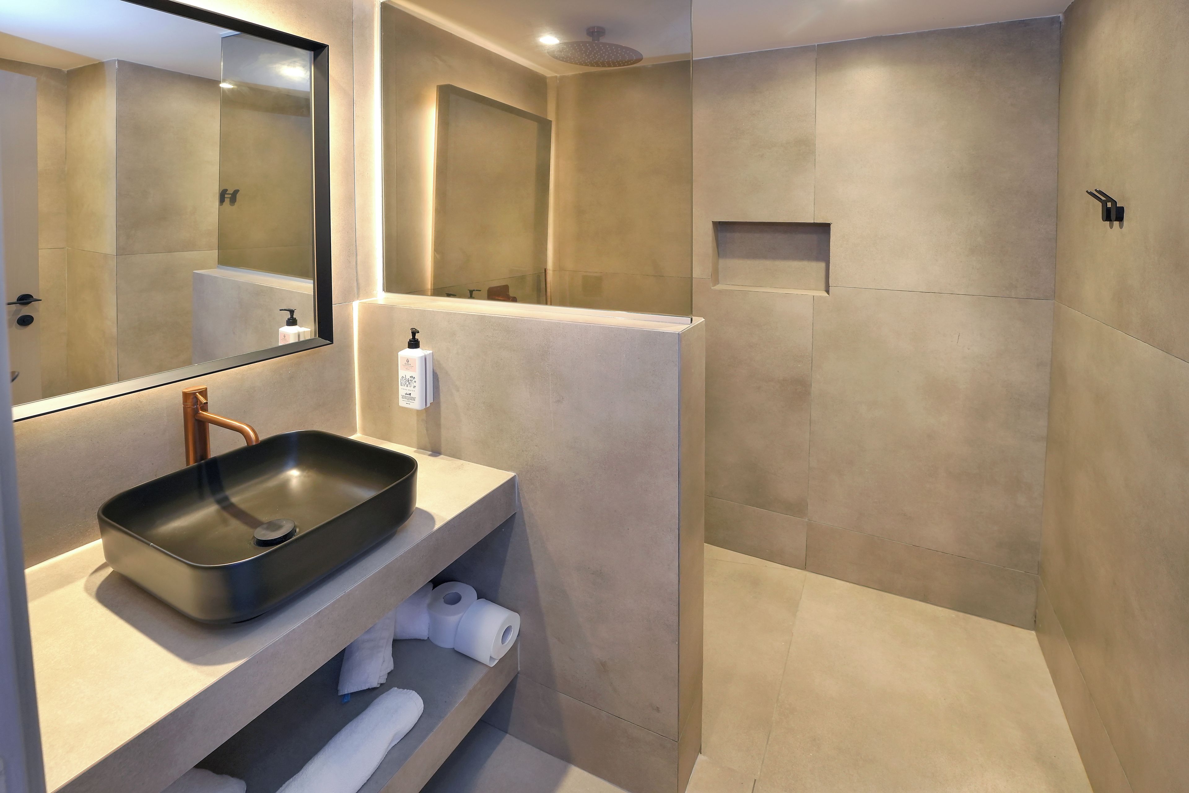 Un bagno moderno con un grande specchio, un lavabo rettangolare, una zona doccia e un porta asciugamani.
