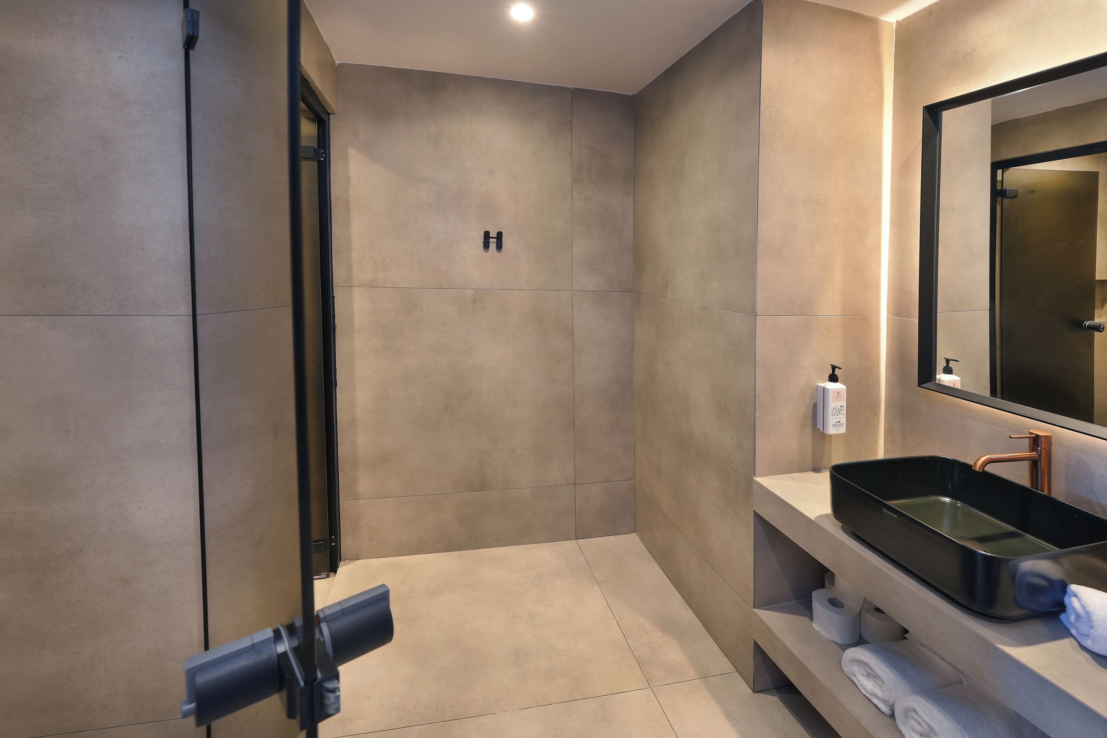 A modern bathroom with a large mirror, a black sink, and a towel rack.