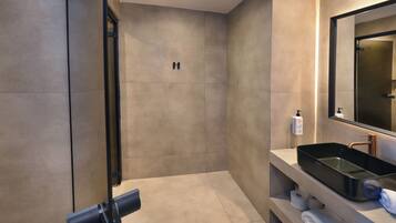 A modern bathroom with a large mirror, a black sink, and a towel rack.