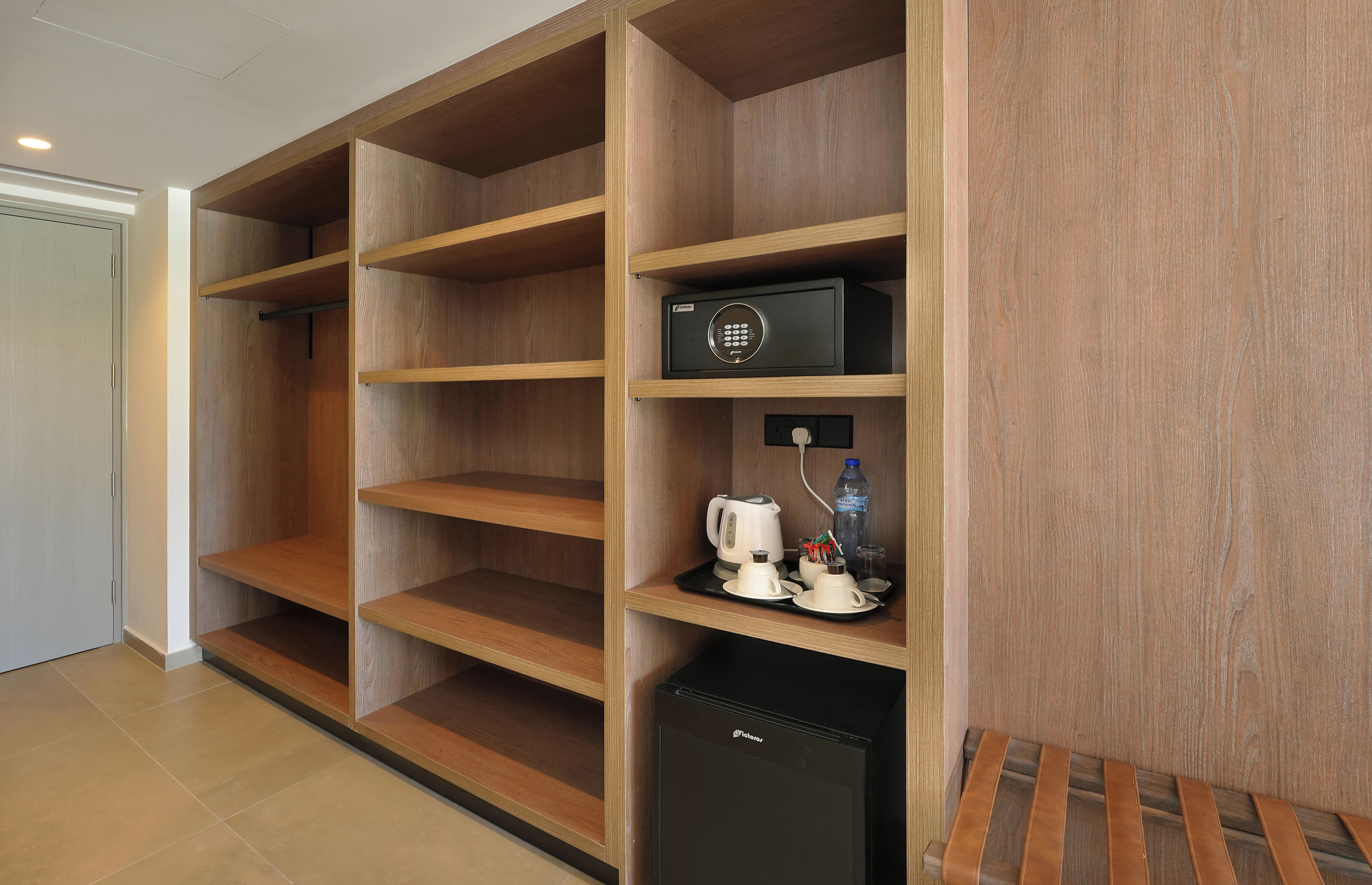 Una habitación de hotel con estanterías de madera, un minibar y un refrigerador pequeño.