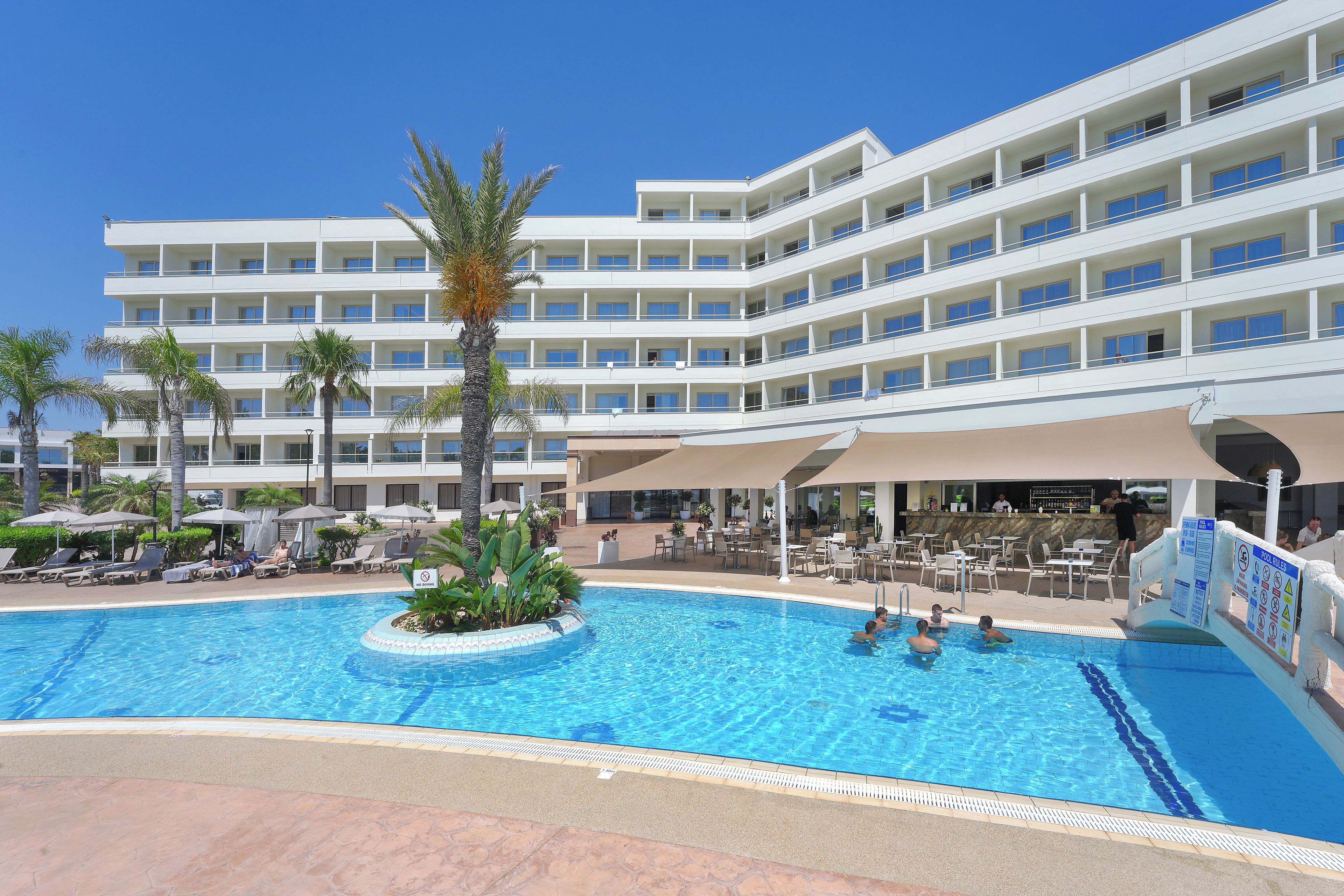 A hotel with a swimming pool, multiple balconies, and outdoor seating areas.