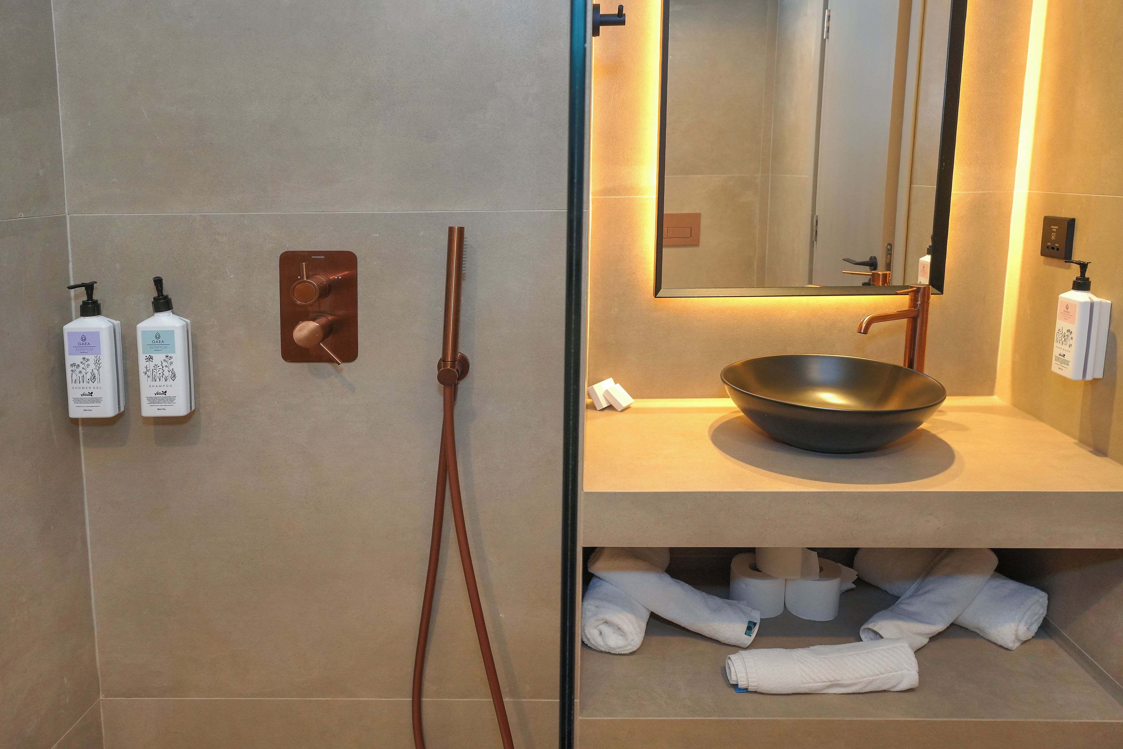 Un baño de diseño moderno, con un espejo grande, un lavabo y dos botellas de gel de ducha y champú.