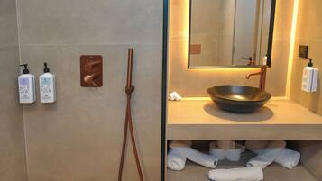 Un baño de diseño moderno, con un espejo grande, un lavabo y dos botellas de gel de ducha y champú.