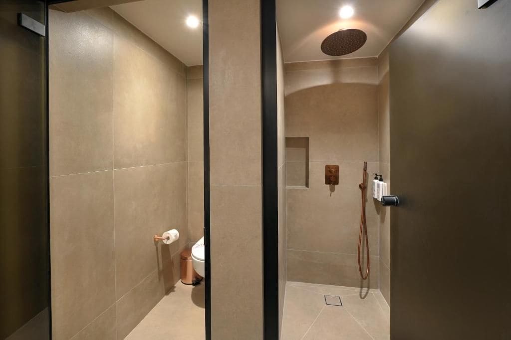 Un baño moderno con mampara de vidrio, inodoro, zona de ducha y toallero.