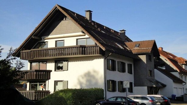 Un edificio a due piani con tetto spiovente, numerose finestre e un balcone.