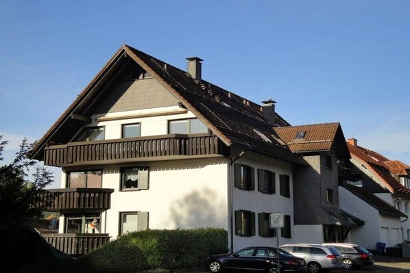 Een gebouw met twee verdiepingen, een schuin dak, veel ramen en een balkon.