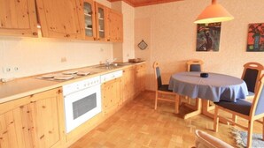 Una cucina con mobili in legno, un fornello e un'area pranzo con tavolo e sedie.