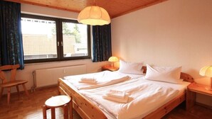 Una camera da letto con un letto di legno, due comodini con lampade, una finestra con tende e un termosifone.
