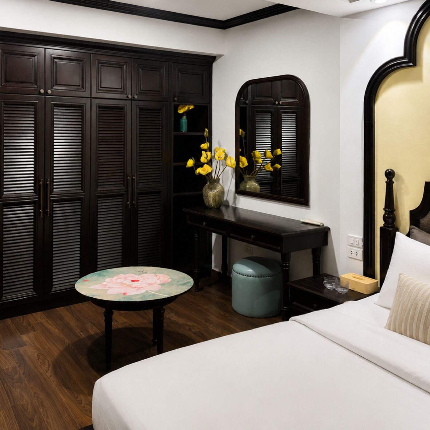 A bedroom with a bed, a desk, a chair, a wardrobe, and a window with a mirror.