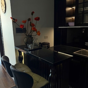 Eine moderne Küche mit schwarzem Arbeitsplatz, einer Vase mit roten Blumen und einem Barhocker.