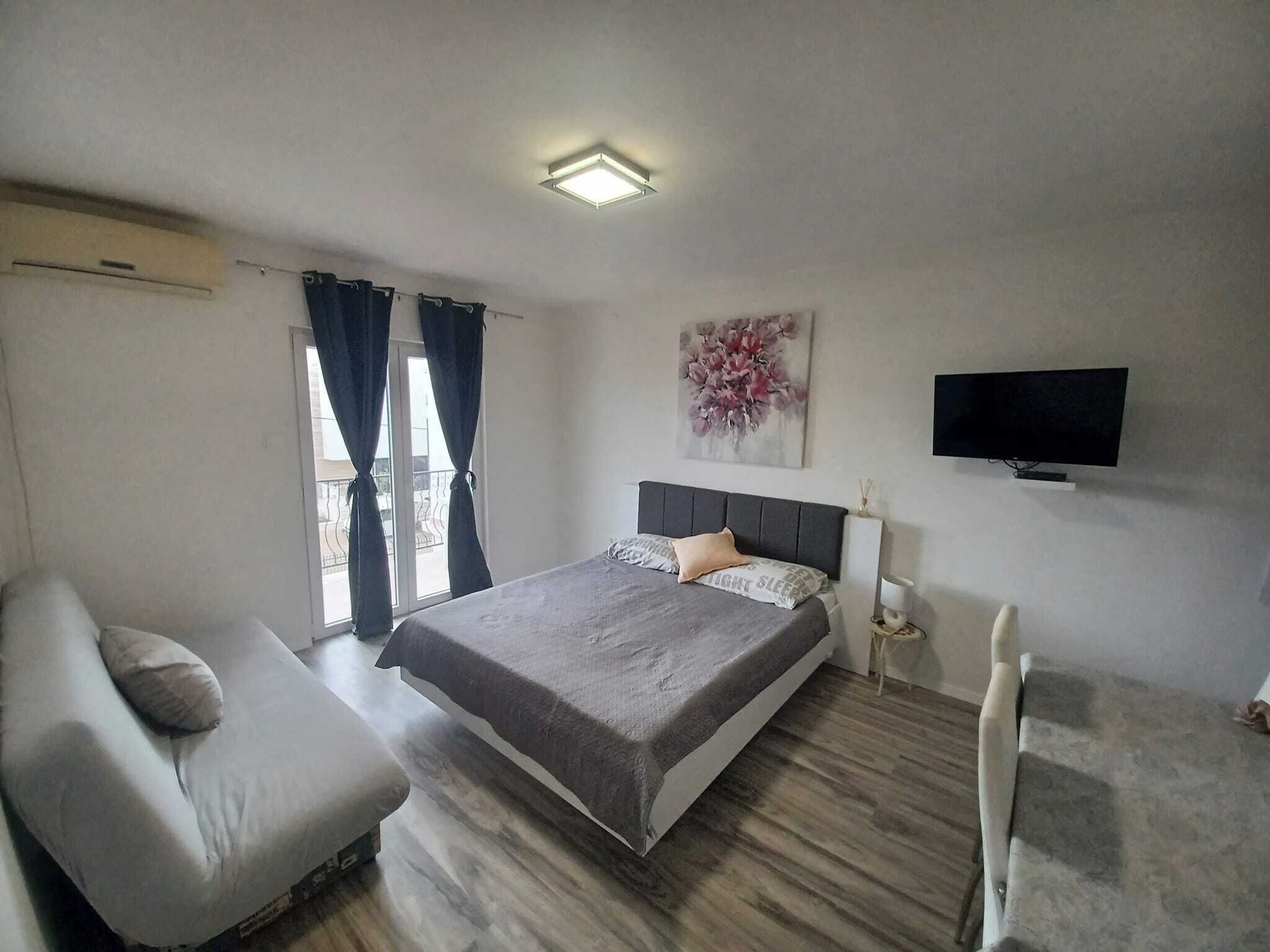 A bedroom with a bed, a chair, a TV, and a painting on the wall.