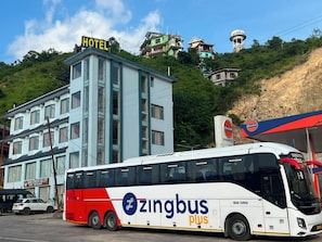 A bus with 'zingbus plus' branding parked in front of a hotel.