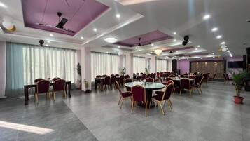 Un salón de conferencias amplio con mesas y sillas redondas, ventiladores de techo e iluminación empotrada.