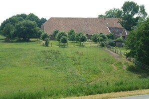 A rural property with a large house, a fenced field, and a pathway leading to the house. - Hof Homfeld Apartment 2 (Jemgum)
