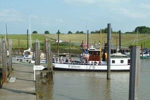 A boat docked at a pier with a wooden walkway leading to it. - Hof Homfeld Apartment 2 (Jemgum)