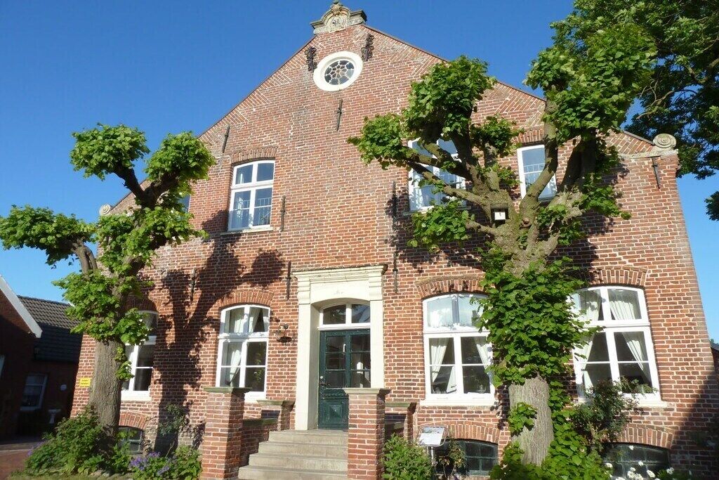 A brick building with a central entrance, multiple windows, and a clock on the facade.