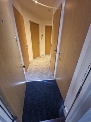 A narrow hallway with wooden doors and a carpeted floor. - Central london 1-Bedroom Apartment with Garden View in London (London)