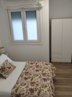 A bedroom with a bed, a window, a wardrobe, and a lamp. - Central, modern accommodations with a terrace overlooking the ocean. Perfect for couples! (Conil de la Frontera)