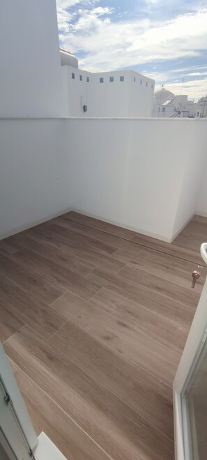 A balcony with a wooden floor, white walls, and a clear sky. - Central, modern accommodations with a terrace overlooking the ocean. Perfect for couples! (Conil de la Frontera)