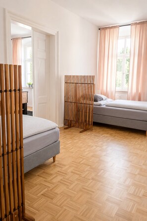 A bedroom with a bed, a sofa, a wooden partition, and a window with curtains. - Gera Apartment Green foosball table 8 guests (Gera)