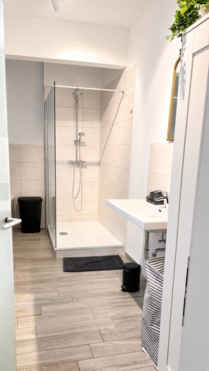 A modern bathroom with a glass-enclosed shower, a white sink, and a mirror. - Gera Apartment Green foosball table 8 guests (Gera)