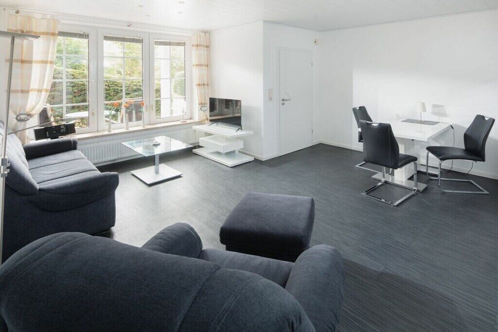 A modern living room with a sofa, ottoman, coffee table, and a TV on a stand.