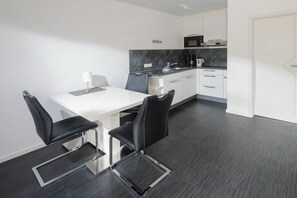 A modern kitchen with white cabinets, a black countertop, and a microwave. - "East" in the Lauwersoog house (Juist)