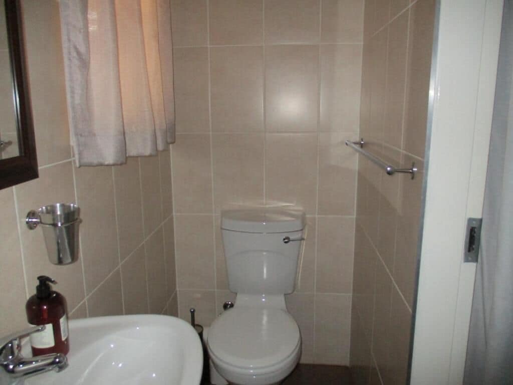 Un baño con inodoro, lavamanos y pasamanos de metal.