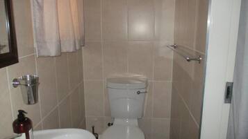 Un baño con inodoro, lavamanos y pasamanos de metal.
