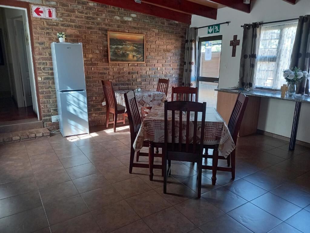 A dining area with a brick wall, a refrigerator, and a table with chairs.