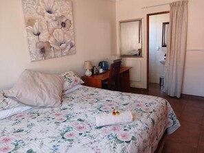 Un dormitorio con cama, escritorio, silla, lámpara y espejo.