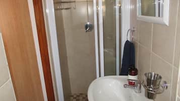 Une salle de bain avec une douche, un lavabo et un miroir.