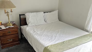 Una camera da letto con un letto, un comodino, una lampada e un'opera d'arte appesa al muro.