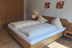 Ein Bett mit Holzrahmen, ein Nachttisch mit Lampe und zwei an der Wand hängende Bilder.