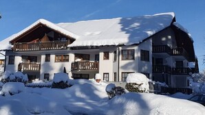 Een hotel met meerdere verdiepingen, balkons en een met sneeuw bedekte dak.