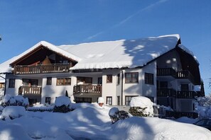 Ein mehrstöckiges Hotel mit Balkonen und einem mit Schnee bedeckten Dach.
