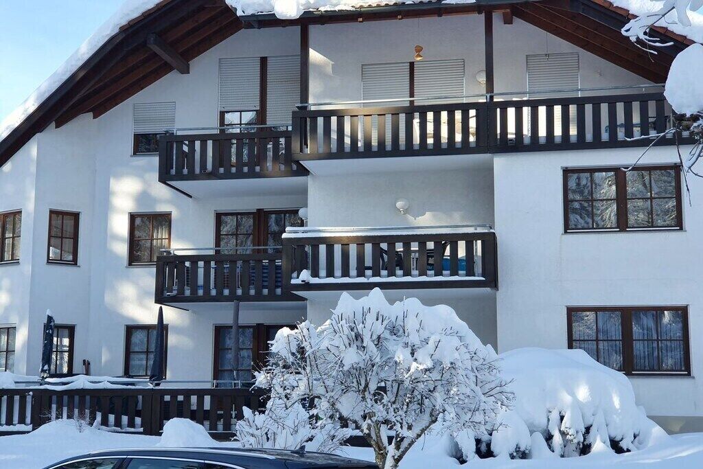 A multi-story building with balconies, windows, and snow accumulation.