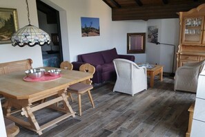 A dining area with a wooden table and chairs, a purple sofa, and a white armchair. - Holiday apartment with 2 bedrooms (Ruhpolding)