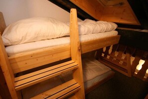 Een stapelbed met een houten trapje en een lattenbodem.