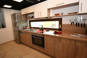 A modern kitchen with wooden cabinets, a stainless steel refrigerator, a built-in oven, and a window above the sink. - Holiday apartment with 2 bedrooms (Ruhpolding)