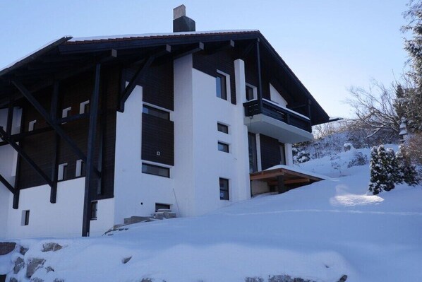 Un edificio moderno de dos pisos con balcón, rodeado de nieve.