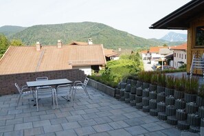 Un patio con mesa y sillas, rodeado por un muro de ladrillo y una vista de la montaña.