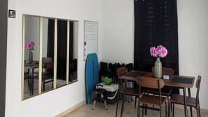 Habitació amb taula de menjador, cadires, mirall, una taula de surf i pissarra.